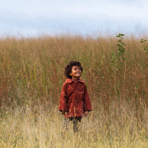 A child wearing the Lillies Dream rosewood corduroy coat happily during an outdoor outing.