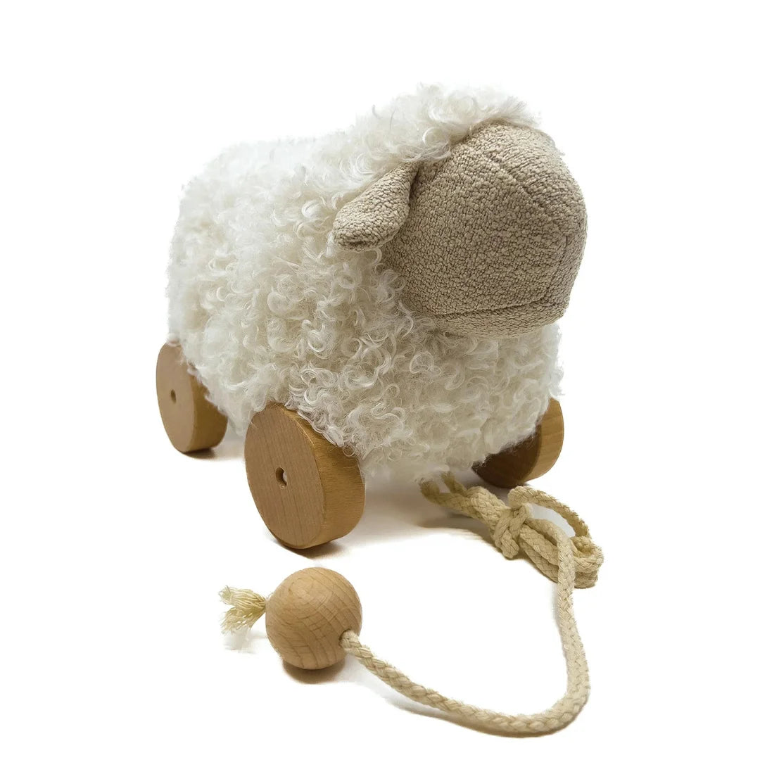 Plush sheep toy with wooden wheels and a pull string on a white background