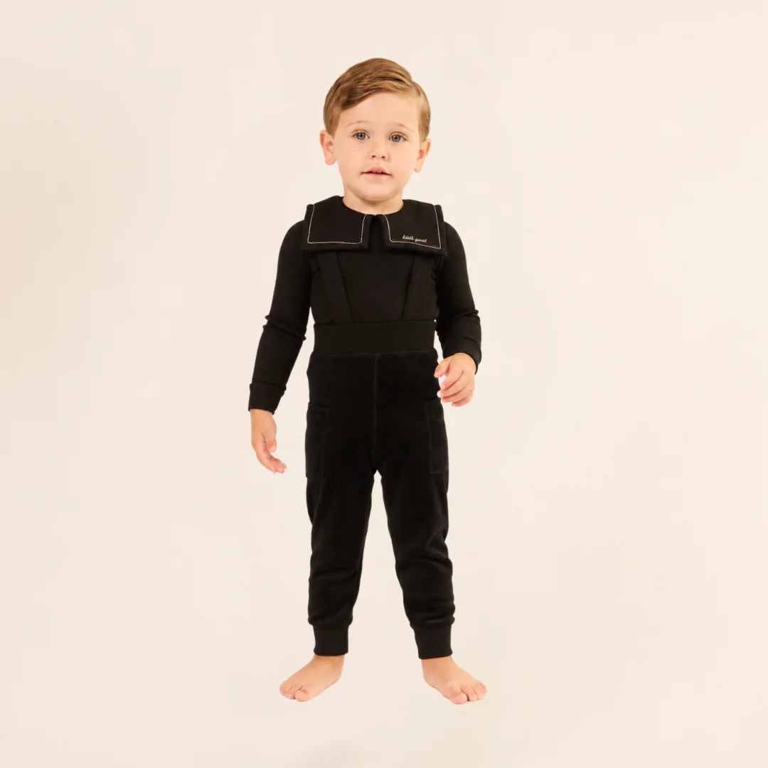 A child styled in the Little Parni black velour overall set during an outing.