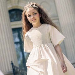 An girl modelling while wearing the Little Tempest ivory heirloom gown.