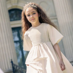 An girl modelling while wearing the Little Tempest ivory heirloom gown.