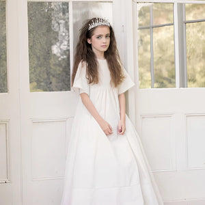 An girl modelling while wearing the Little Tempest ivory heirloom gown.