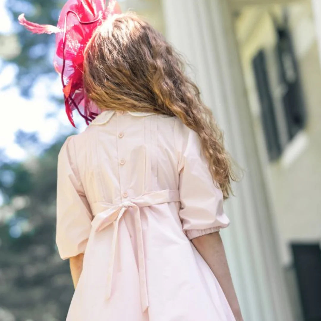 A child wearing the Little Tempest pink taffeta gown at a formal celebration back side.
