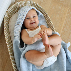 A happy baby wrapped in the soft Little Threads hooded bath towel after a bath.