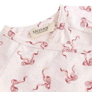 A high-resolution close-up of the organic cotton knit texture and signature bow print.
