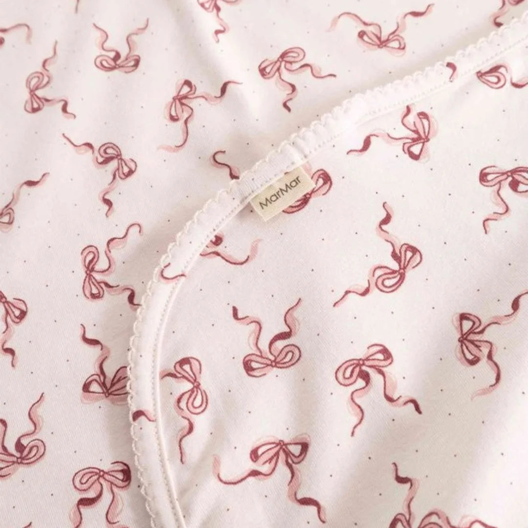 A high-resolution close-up of the organic cotton knit texture and Alida bow print.