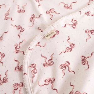 A high-resolution close-up of the organic cotton knit texture and Alida bow print.