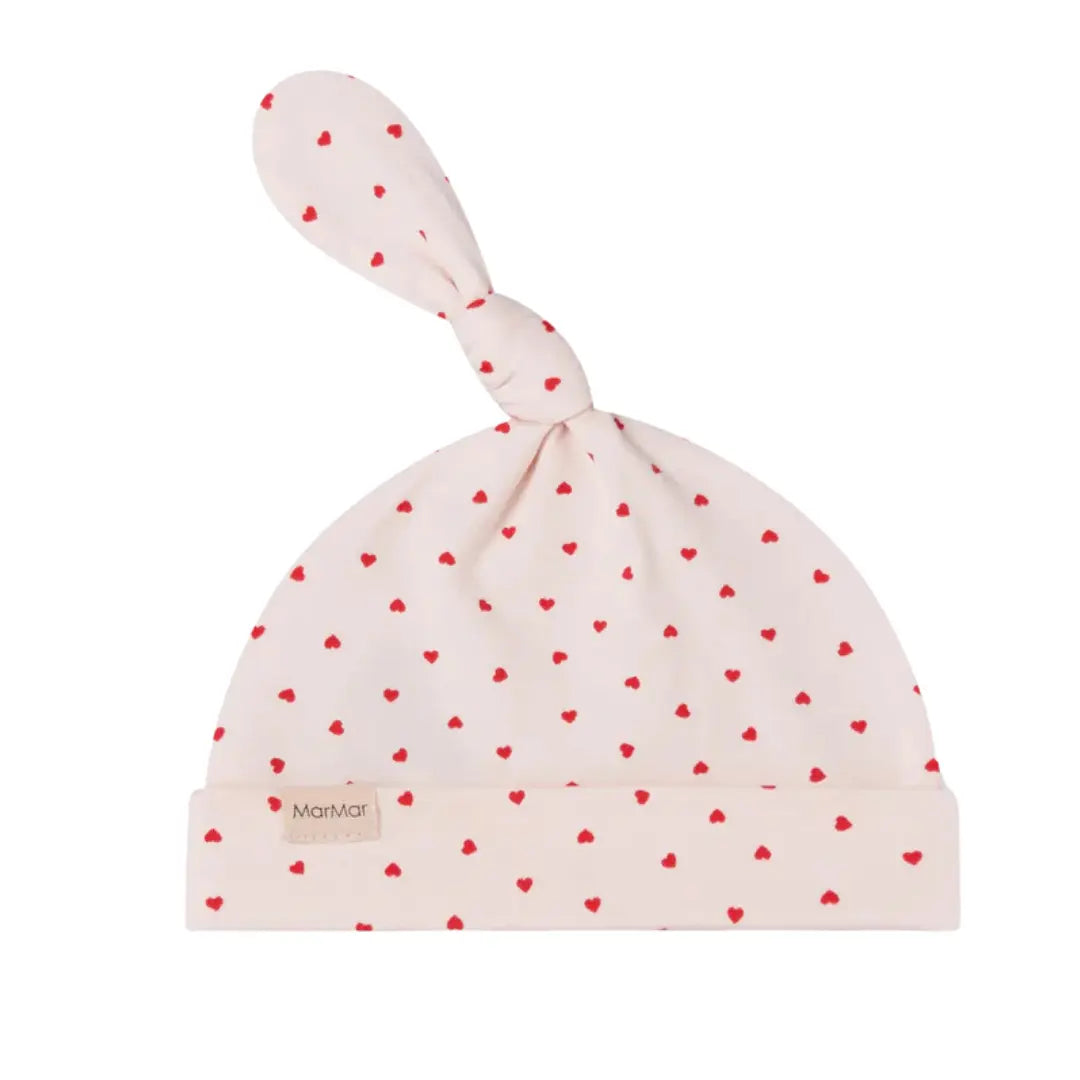 A breathtaking MarMar Copenhagen Aiki hat in a soft cream color featuring a refined pink "Happy Hearts" print and a sophisticated knotted top.