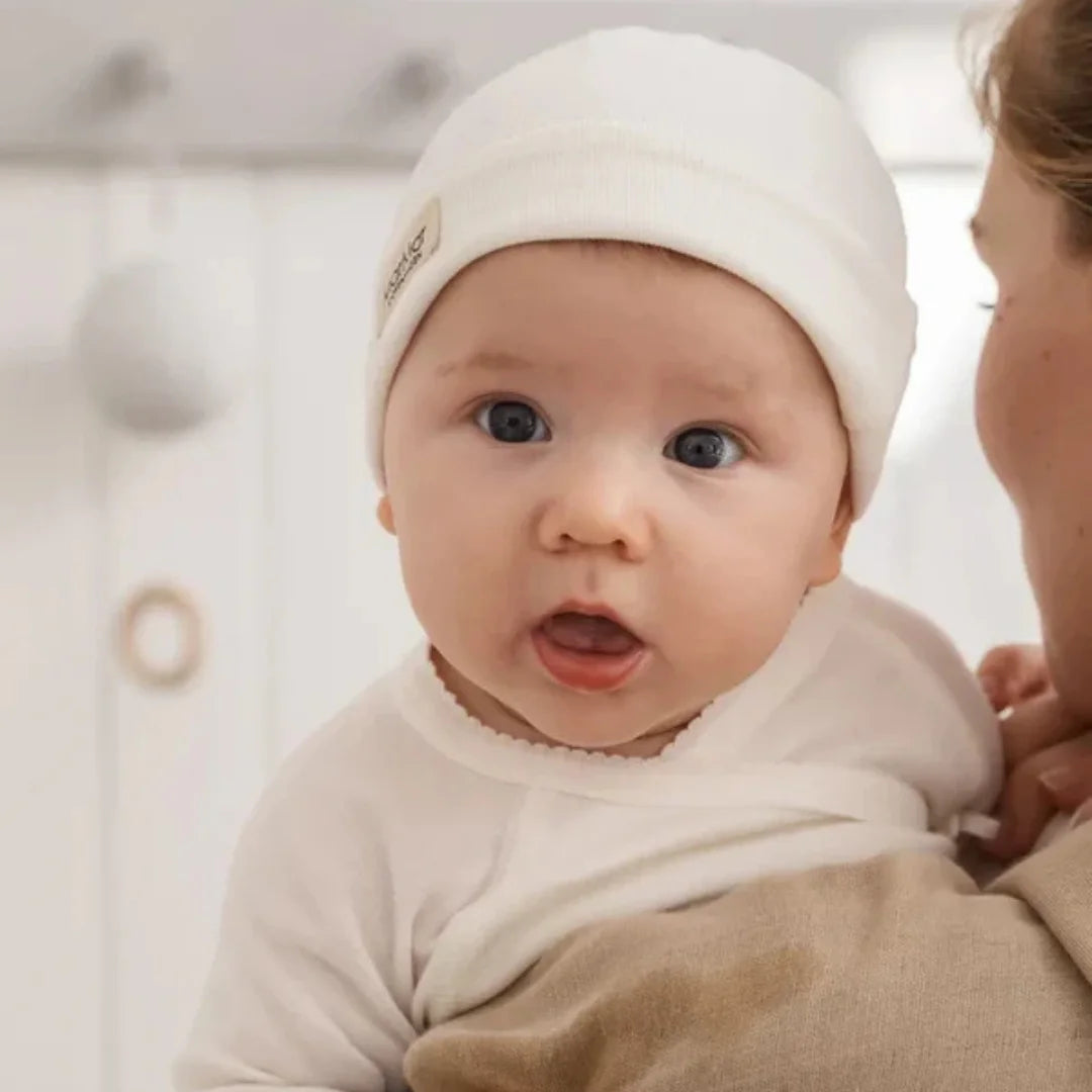 A newborn baby styled in the MarMar Copenhagen Tuti wrap set on a luxury blanket.