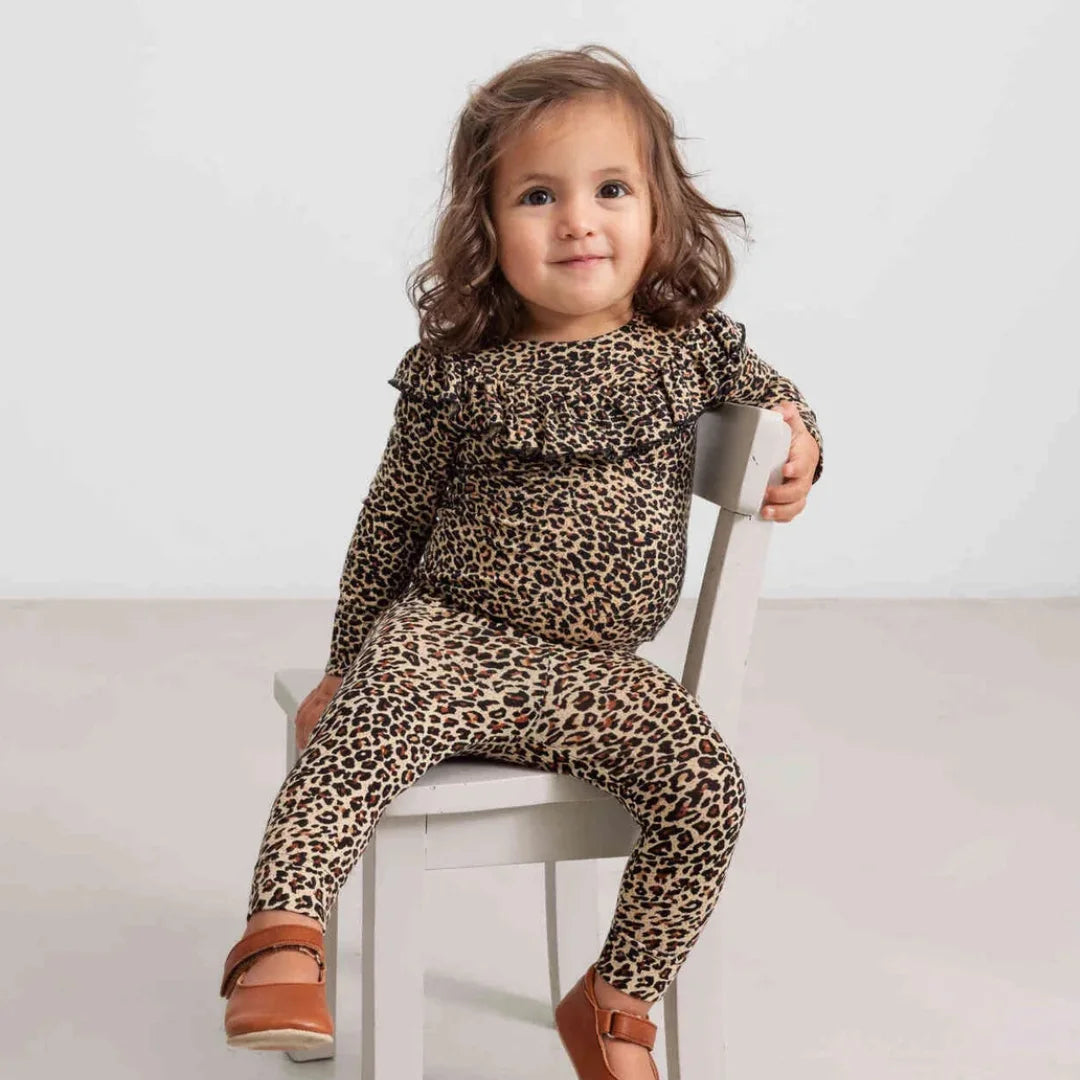 A child wearing the MarMar Copenhagen leopard berta legging set comfortably during an outdoor playground outing.