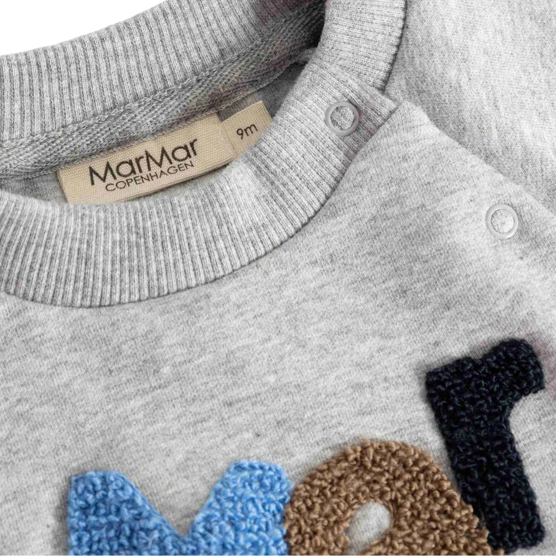 A high-resolution close-up of the plush fleece texture, collar, and signature logo detail.