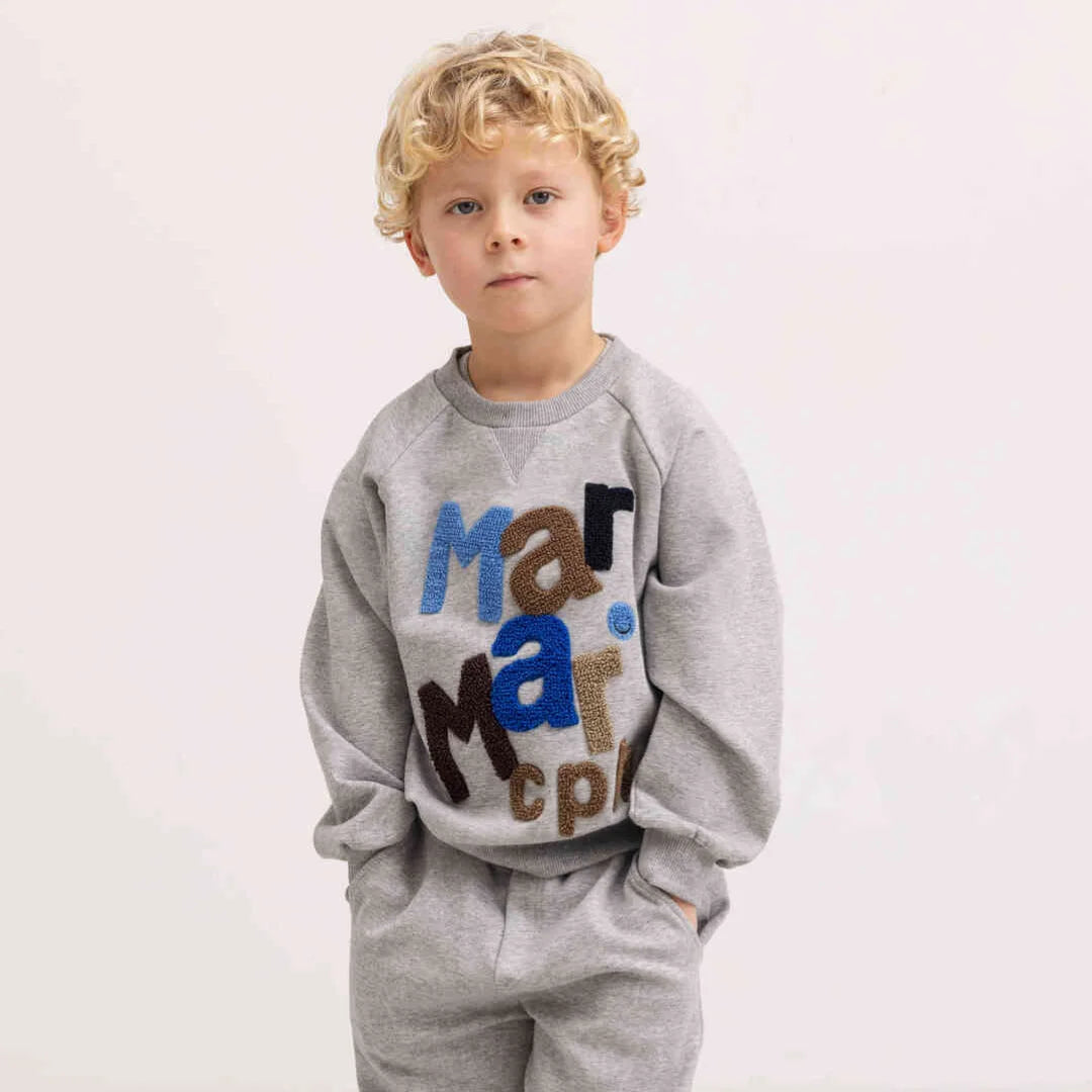 A child wearing the MarMar Copenhagen muddy sweatshirt comfortably during an outdoor playground outing.