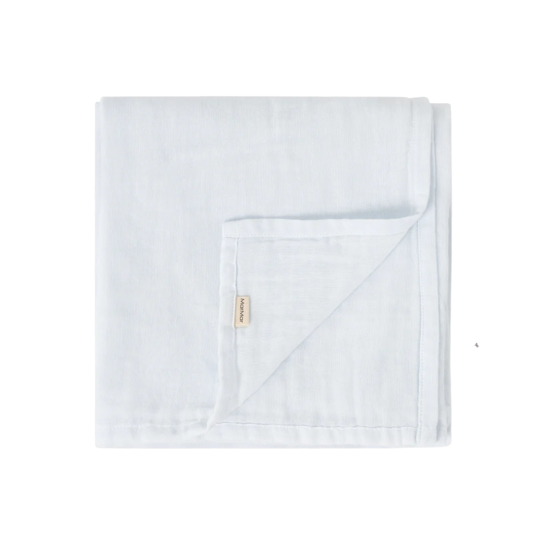 A folded light blue muslin blanket with a small beige fabric brand tag, shown on a plain white background.