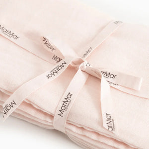 A folded light pink fabric item tied with a matching ribbon printed with the brand name 'Matrimony'.