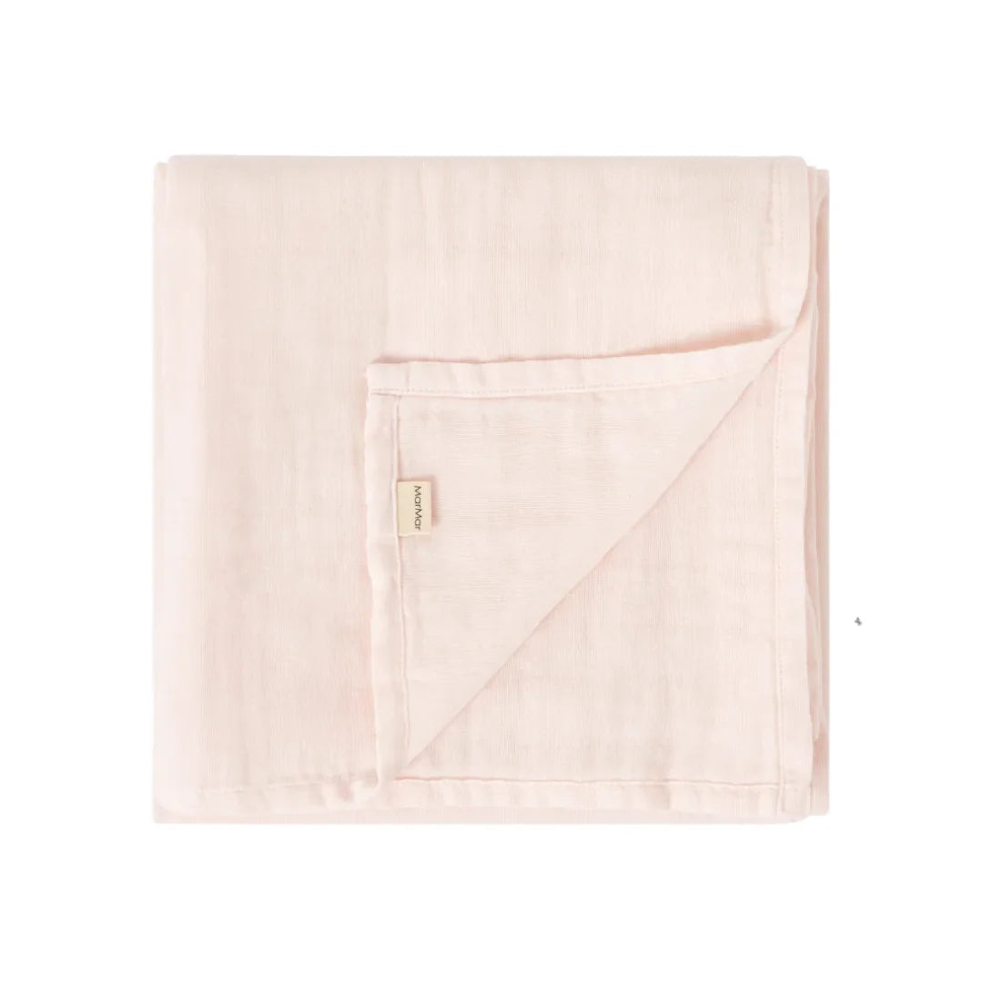 A folded light pink muslin blanket with a small beige brand tag, shown on a plain white background.