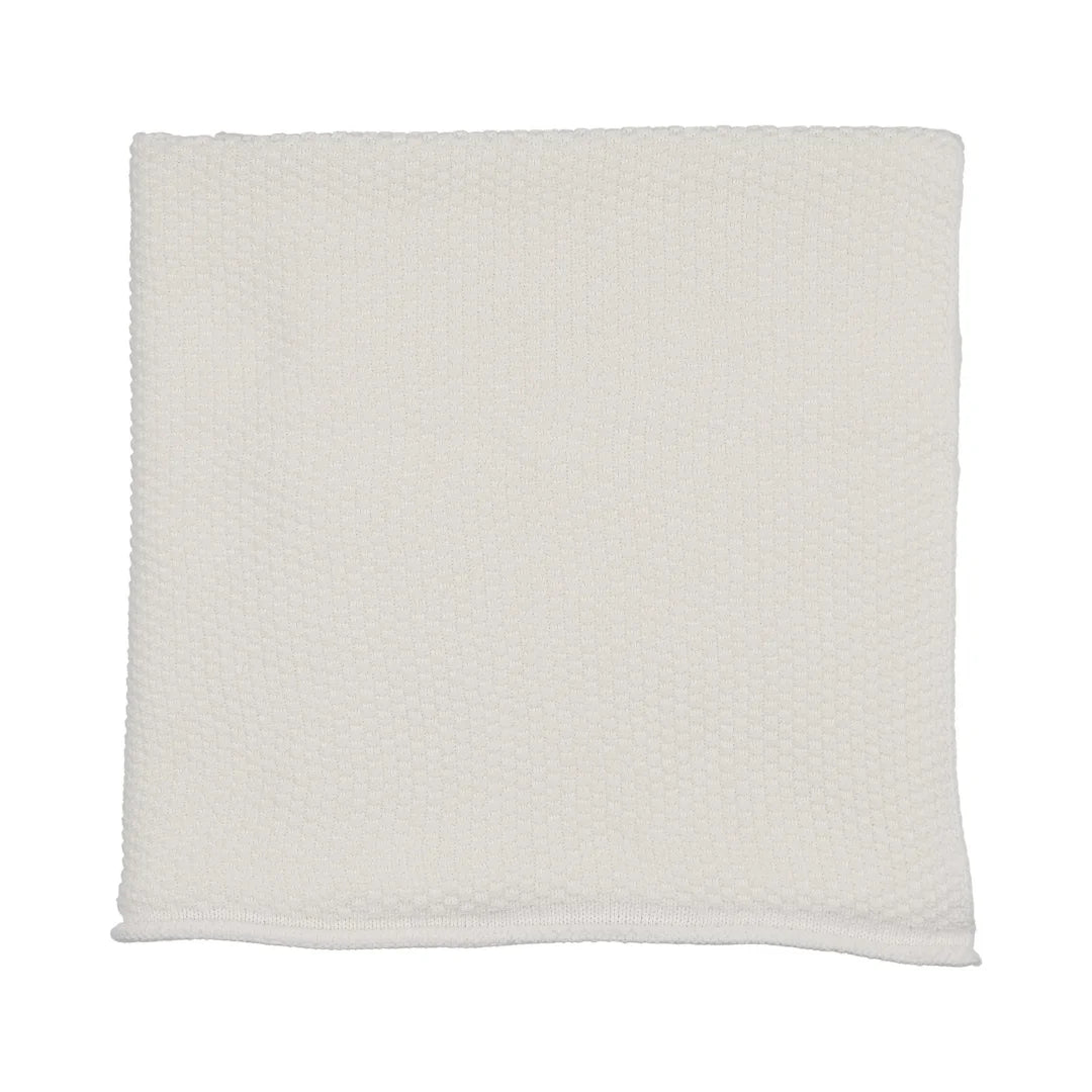 A flat-lay view of the Mema Knits ivory embroidered edge knit blanket.