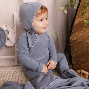 An infant styled in the Mini Label blue velour footie during a portrait session.