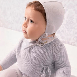 An infant styled in the Mini Label blue wrap cardigan and bonnet during a portrait session.