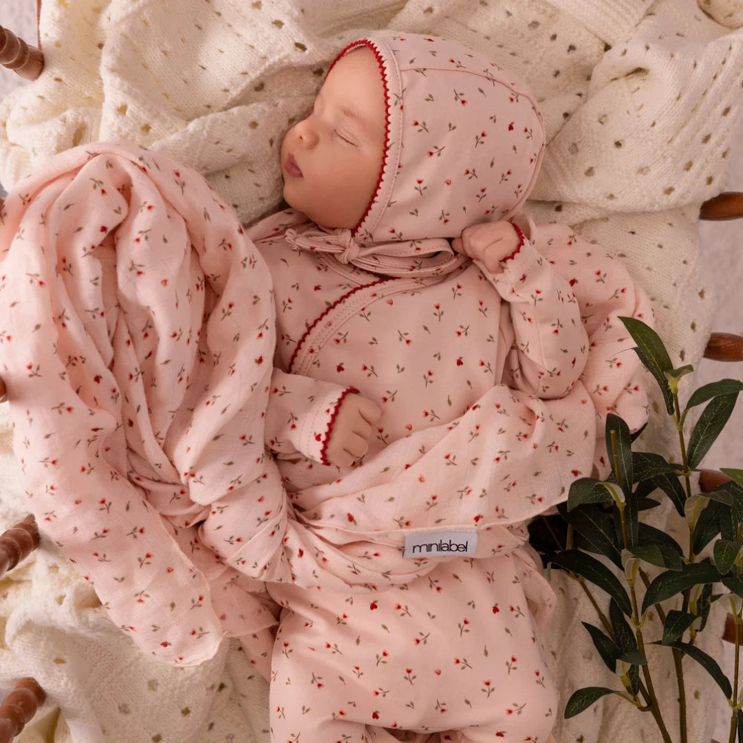 An infant styled in the Mini Label pink heart kimono footie and bonnet set during a portrait session.