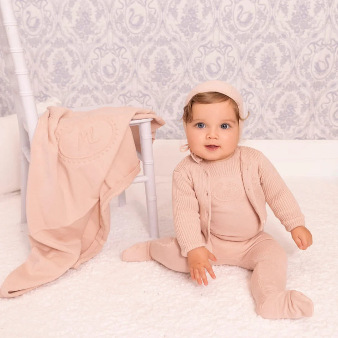 A newborn infant styled in the Mini Label pink knit footie set during a portrait session.