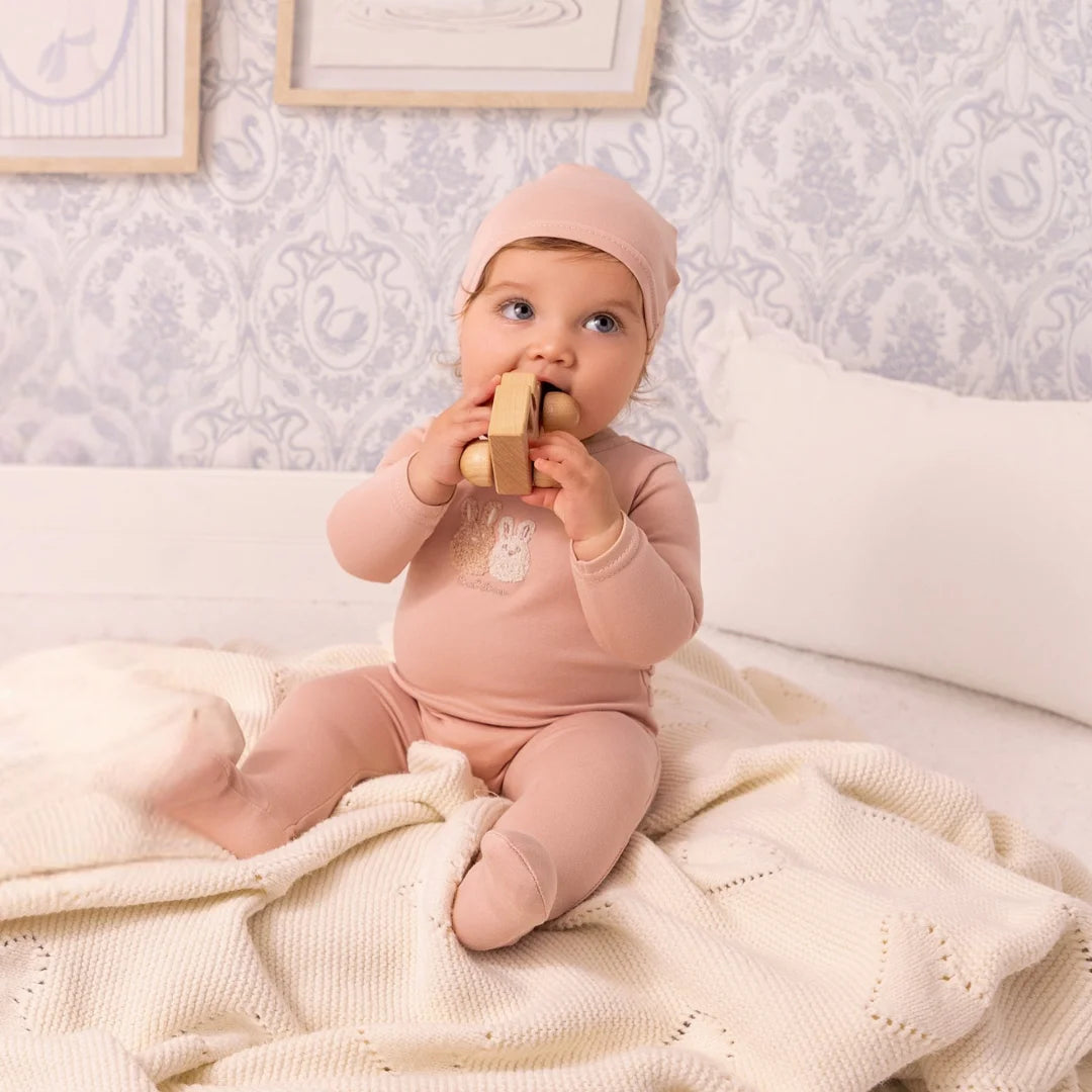 A newborn baby wearing the Mini Label pink sherpa footie comfortably during a brisk outdoor walk.
