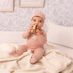 A newborn baby wearing the Mini Label pink sherpa footie comfortably during a brisk outdoor walk.