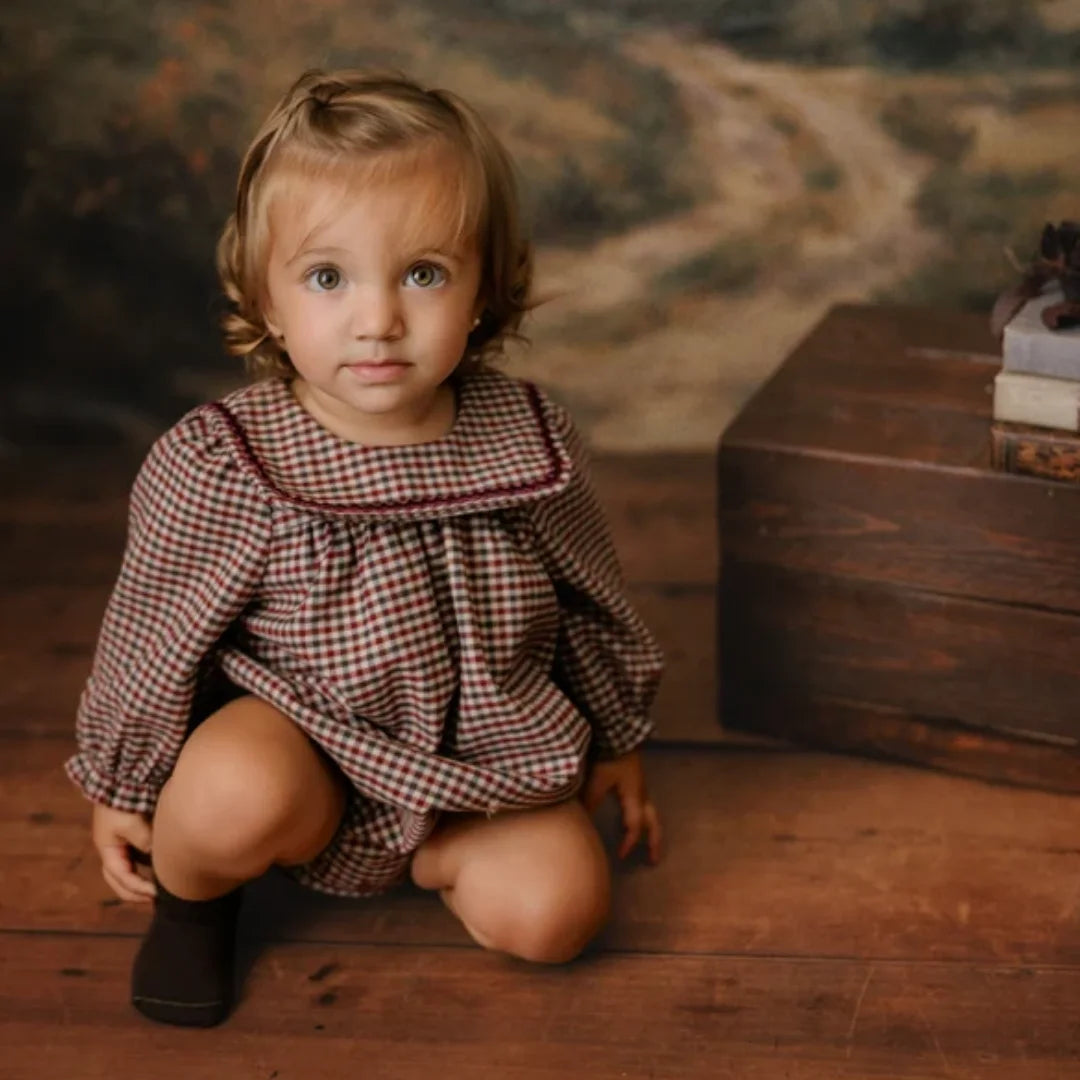A child styled in the Mini P burgundy velvet romper during a holiday portrait session.