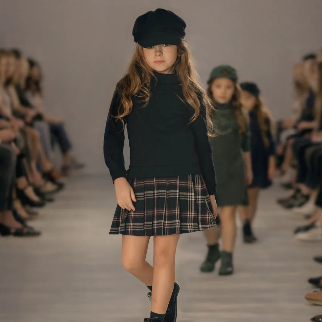 A young girl wearing the Mode Avant sweatshirt dress paired with boots during a fashion runaway.