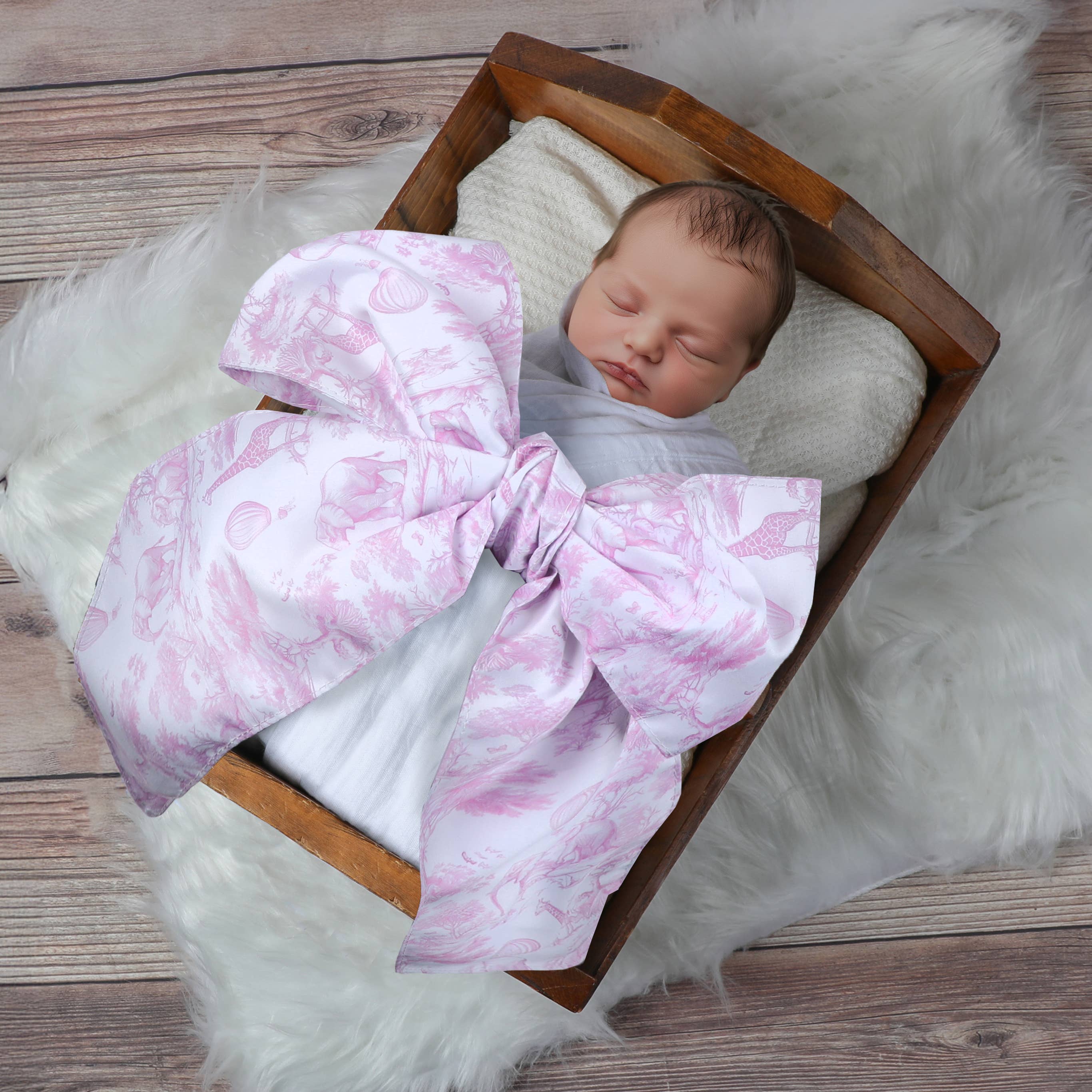 Newborn baby wrapped in a pink and white patterned blanket in a wooden crib.