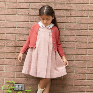 A child wearing the Nou Nelle rust cardigan during an outdoor 