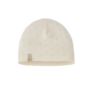 An off-white knit beanie hat with a subtle dotted pattern and a small fabric brand tag on the lower left cuff, shown against a plain white background.
