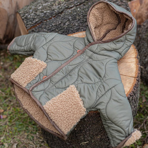Green quilted jacket with brown sherpa lining on a tree stump