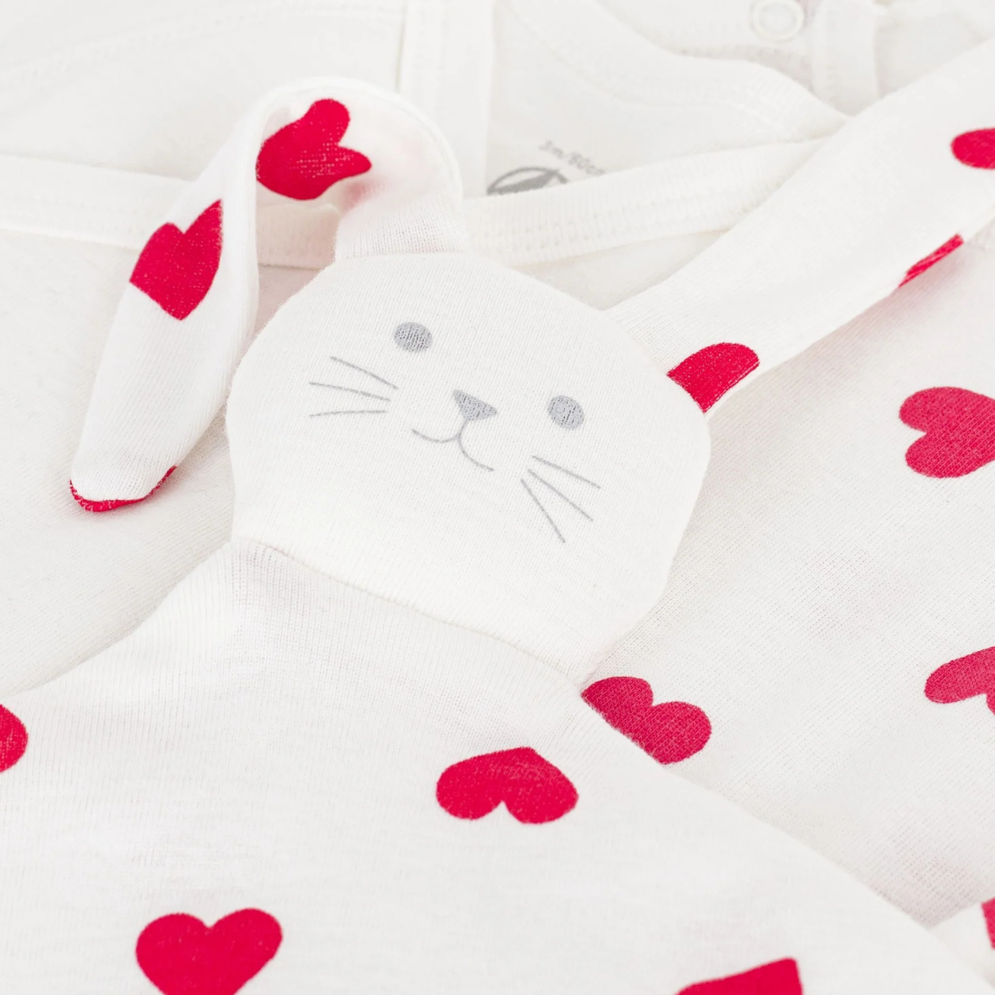 A close-up of the soft heart-print fabric and the plush doudou companion.