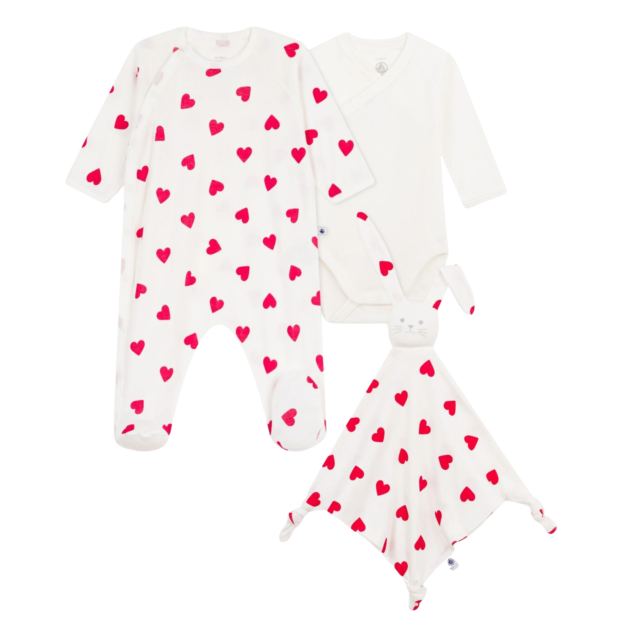 A front view of the Petit Bateau three-piece newborn set, including heart-print footie, white bodysuit, and doudou.