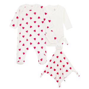 A front view of the Petit Bateau three-piece newborn set, including heart-print footie, white bodysuit, and doudou.