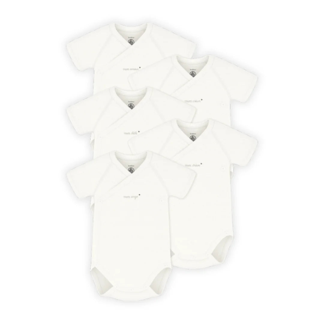 Multiple white baby rompers stacked on a white background