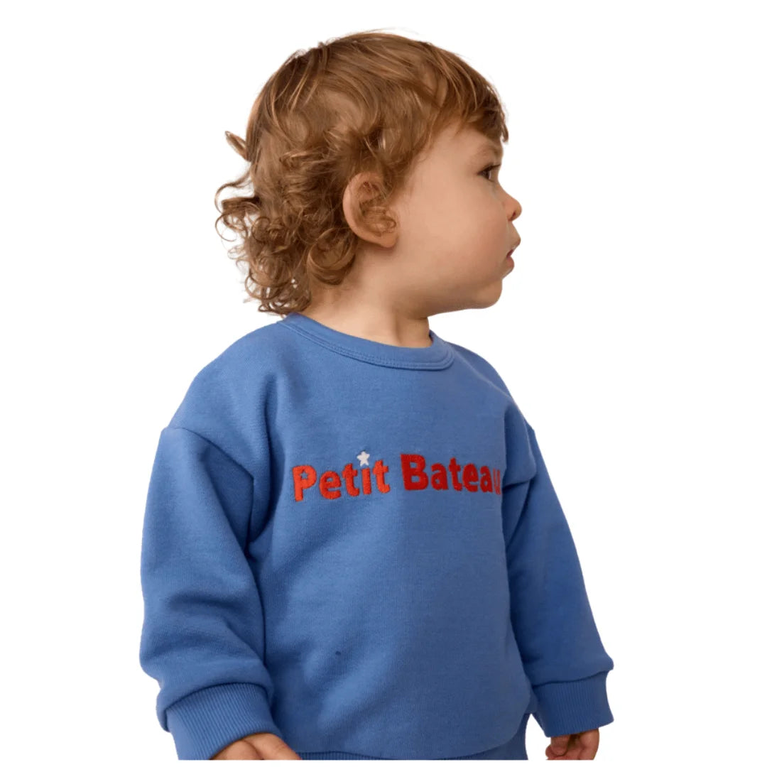A breathtaking Petit Bateau baby sweatshirt featuring an immaculate blue palette, ribbed cuffs, and the iconic heritage logo.