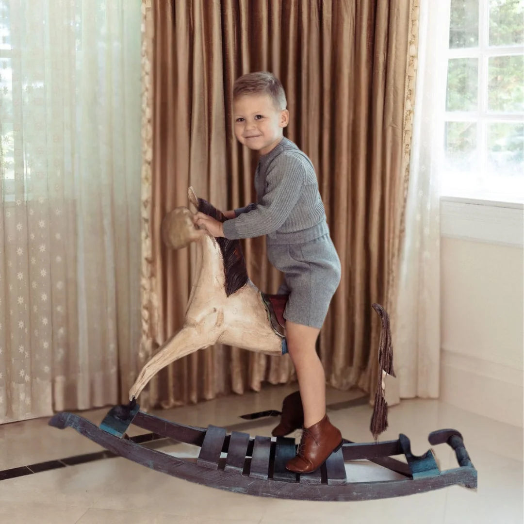 A toddler wearing the Pompomme grey wool bermuda set during a family gathering.