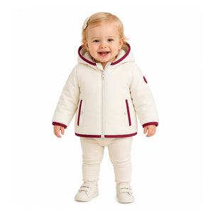 A toddler styled in the Pramie red binding jacket during an outdoor holiday outing.