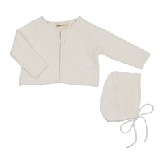 A baby knit three-piece outfit set in off-white, featuring a long-sleeve cardigan, a bonnet with tie strings, and a small bootie, laid out on a white background. The brand name 'MEMA KITS' is visible on the inner neck label.