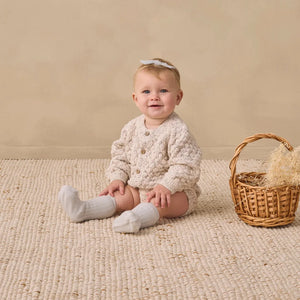 A toddler wearing the Quincy Mae natural cardigan comfortably 