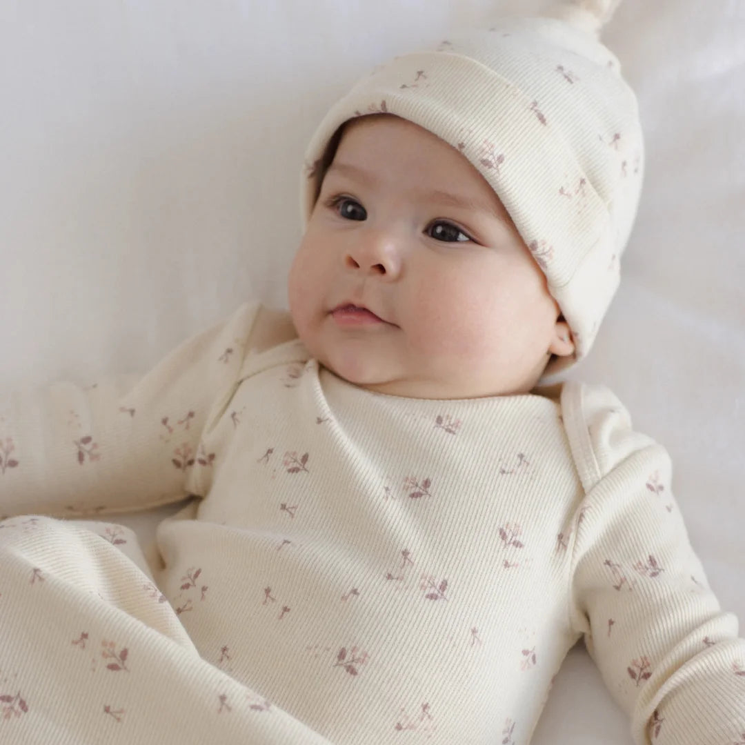 An infant resting peacefully while wearing the Quincy Mae Fall Ditsy knotted gown and hat.