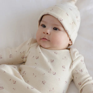 An infant resting peacefully while wearing the Quincy Mae Fall Ditsy knotted gown and hat.
