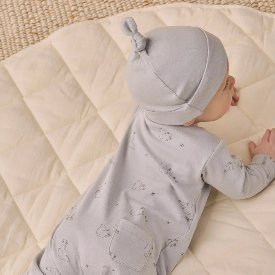 An infant resting peacefully while wearing the Quincy Mae cloud knotted baby hat.