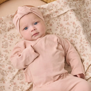 An infant wearing the Quincy Mae dusty rose knotted headband comfortably during an outing.