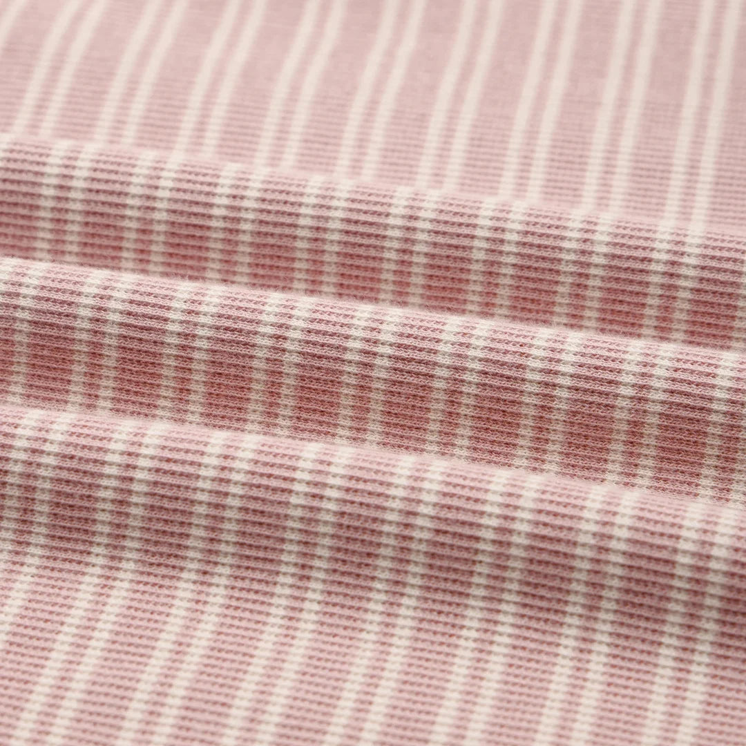 A high-resolution close-up of the soft organic cotton knit texture and delicate dusty rose stripe pattern.