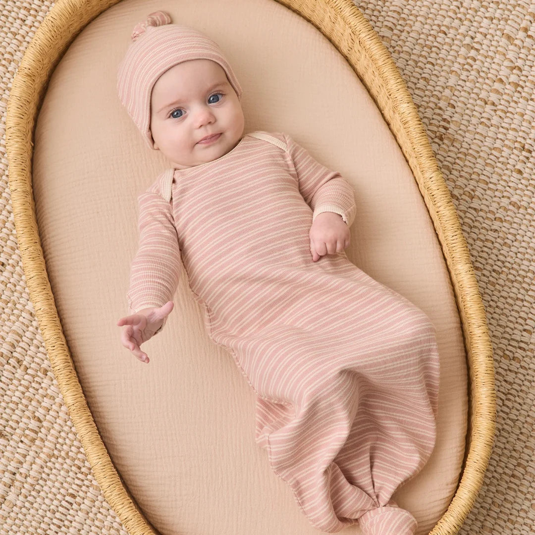An infant resting peacefully while wearing the Quincy Mae dusty rose microstripe knotted gown and hat.