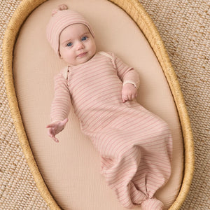 An infant resting peacefully while wearing the Quincy Mae dusty rose microstripe knotted gown and hat.