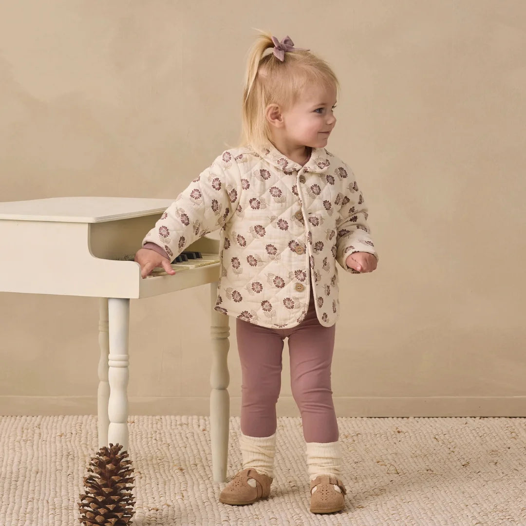A toddler wearing the Quincy Mae fall floral quilted jacket comfortably