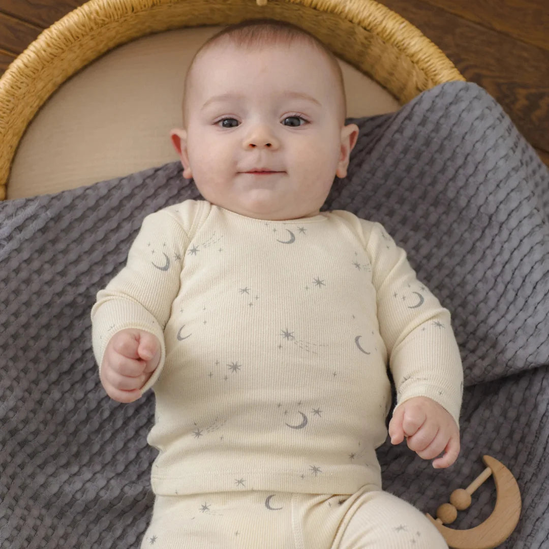 An infant playing comfortably while wearing the Quincy Mae celestial tee and leggings.